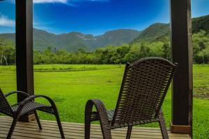 two chairs sitting on a porch with a view of a field at Pousada Índios Coroados in Praia Grande