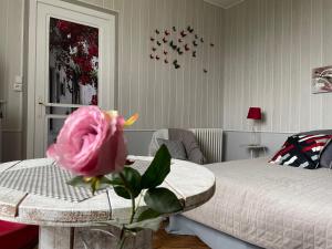 a pink rose sitting on a table in a bedroom at Le Chalet des Vignes in Saint-Laurent-des-Vignes