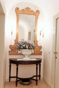 um vaso com flores em uma mesa em frente a um espelho em Dimora del Castellano GREEN HOUSE em Gioia del Colle