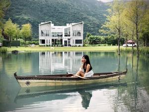 una mujer sentada en un bote en el agua en 靜樹湖民宿Jing Shuhu B&B, en Shuhu