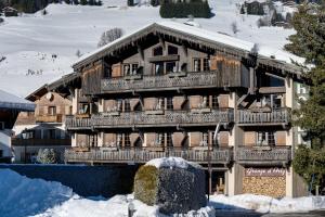 a large wooden building with snow on the ground at Hôtel La Grange d'Arly in Megève