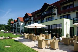 a patio with tables and chairs and an umbrella at Hochwälder Wohlfühlhotel in Losheim