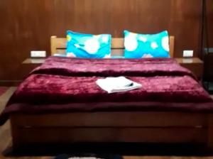 a bedroom with a bed with purple sheets and blue pillows at Bluepine Cottages Pangot by Nature Nests in Nainital +18 photos