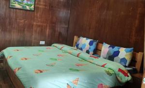 a bed with a green comforter and two pillows at Bluepine Cottages Pangot by Nature Nests in Nainital