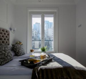 bandeja de comida en una cama con ventana en Warsaw Seasons by Alluxe Boutique Apartments, en Varsovia