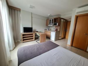 a bedroom with a white bed and a kitchen at BSB FLAT - MELHOR LOCALIZAÇÃO in Brasilia +10 photos
