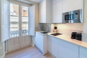 a kitchen with white cabinets and a sink and a window at Cordoba Home Center Suites & Free Private Parking in Córdoba