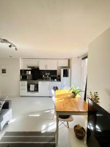 a kitchen with white cabinets and a wooden table at Dupleix Centre Ville Montlhéry Parking 30min Paris in Montlhéry