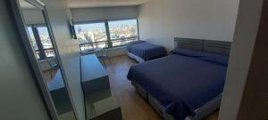 1 dormitorio con cama azul y espejo en Que mejor vista del Obelisco piso a la calle Corrientes en Buenos Aires