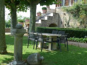 einen Tisch und Stühle in einem Garten mit einem Gebäude in der Unterkunft Clos de Mont July, chambres avec vue et terrasse dans demeure historique in Ceyzériat