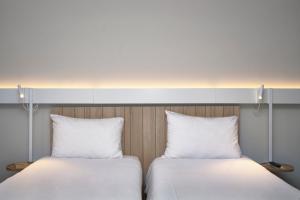 2 camas con almohadas blancas juntas en Ibis Annecy - Cran-Gevrier en Annecy