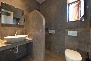 a bathroom with a sink and a toilet and a mirror at Kalamitsi Hotel in Kardamyli