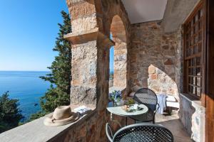 a patio with a table and chairs and the ocean at Kalamitsi Hotel in Kardamyli