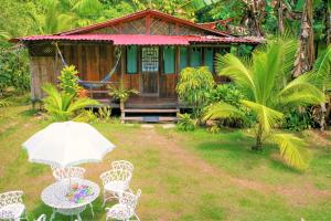 a house with a table and chairs and an umbrella at Ocean Forest Ecolodge in San Pedrillo
