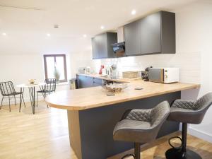 a kitchen with a counter and some chairs in it at Scandic Apartment, Ulverston in Ulverston
