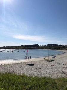 una playa con gente y barcos en el agua en Le crabe rouge en Groix