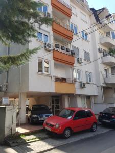 een rode auto geparkeerd voor een gebouw bij Petar's Apartment in Skopje