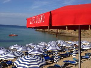 a group of chairs and umbrellas on a beach at Hotel Villa Giulia in Porto Azzurro