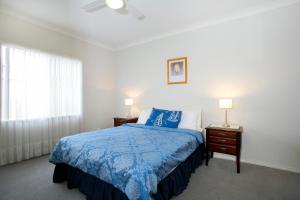 a bedroom with a blue bed with two night stands and two lamps at All Seasons Port Elliot Holiday House in Port Elliot