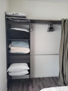 un armario con una estantería negra con toallas plegadas en Le bel'air appartement chaleureux et calme oyonnax, en Oyonnax