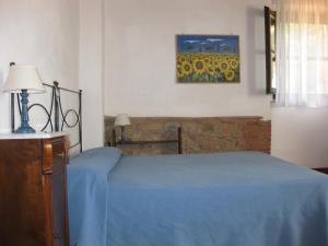 ein Schlafzimmer mit einem blauen Bett und einem Gemälde an der Wand in der Unterkunft Agriturismo Bronzivalle in Riotorto
