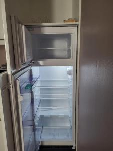 an empty refrigerator with its door open in a kitchen at Le bel'air appartement chaleureux et calme oyonnax in Oyonnax