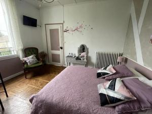 Un dormitorio con una cama con sábanas moradas y una ventana en Le Chalet des Vignes, en Saint-Laurent-des-Vignes