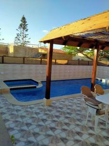 a pavilion with a table and chairs and a pool at قرية رمسيس الكيلو45 الساحل الشمالي in Borg El Arab
