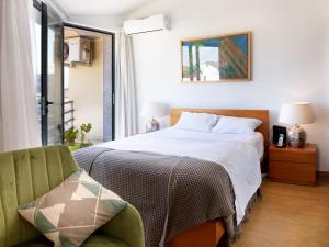 a bedroom with a bed and a green chair at Anthero Quental Boutique Apartment in Ponta Delgada