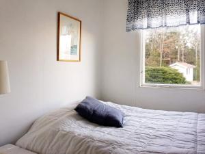 a bed with a blue pillow in a room with a window at 6 person holiday home in BRASTAD in Brastad