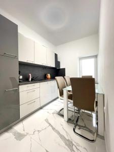 a kitchen with white cabinets and a table and chairs at Luxury Apartment ASIA 2 Rijeka in Rijeka