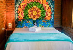 een bed met twee handdoeken en een bloemrijk hoofdeinde bij Pousada Guaiamum in Itacaré