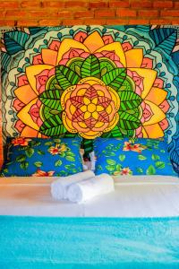 a bed with a wall with a flower mural at Pousada Guaiamum in Itacaré