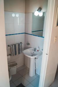 a white bathroom with a sink and a mirror at Courtesy Apartments Aruba in Oranjestad