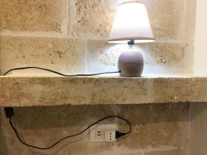 a lamp sitting on a wall next to a lightswitch at Casetta dello Scrittore in Ostuni