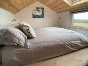 ein großes Bett in einem Zimmer mit Fenster in der Unterkunft The Ashmere Tiny House in Coldingham