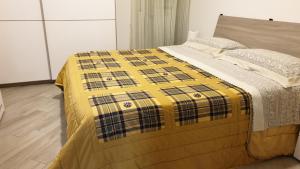un letto con una coperta gialla e nera sopra di Casa Nonna Graziella a Gela