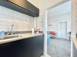 a kitchen with black cabinets and a sink at Bella House - 3 bed house in Glasgow in Glasgow