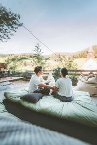 un paio di persone sedute su un grande letto di Bubble-Tent Elzach inklusive Hot Tube Badefass a Elzach