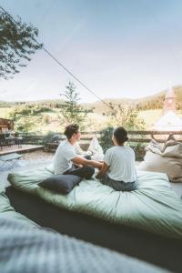 a couple of people sitting on a large bed at Bubble-Tent Elzach inklusive Hot Tube Badefass in Elzach