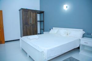 un letto bianco con lenzuola e cuscini bianchi in una stanza di Maha Oya Lodge a Wayikkal