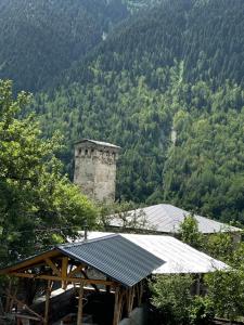 a building with a tower in front of a mountain at Apartment Jorjo Mestia in Mestia
