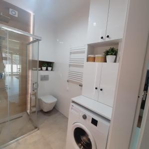 a white bathroom with a washing machine and a toilet at Lux Apartment parking gratis in Złotów