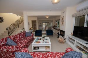 a living room with red couches and a tv at Villa Helena in Ayia Napa