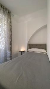 a bed in a white room with a window at Palazzo Framì in Acireale