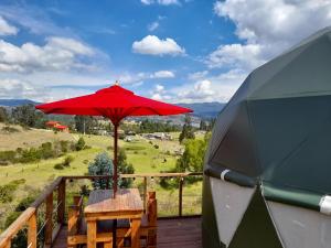 un ombrello rosso seduto sopra un ponte di legno di Glamping La Cacica a Guatavita