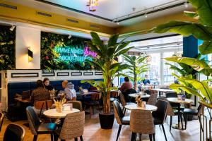 people sitting at tables in a restaurant with plants at Hotel Pauw in Nijmegen