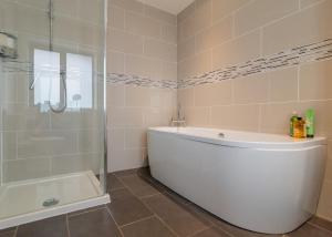 a white bath tub sitting next to a white toilet at Laundimer House Bed & Breakfast in Corby
