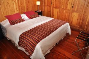 un grande letto in una camera con pareti in legno di Monasterio Hotel Boutique a San Carlos de Bariloche