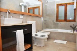 a bathroom with a toilet and a sink and a tub at Monasterio Hotel Boutique in San Carlos de Bariloche